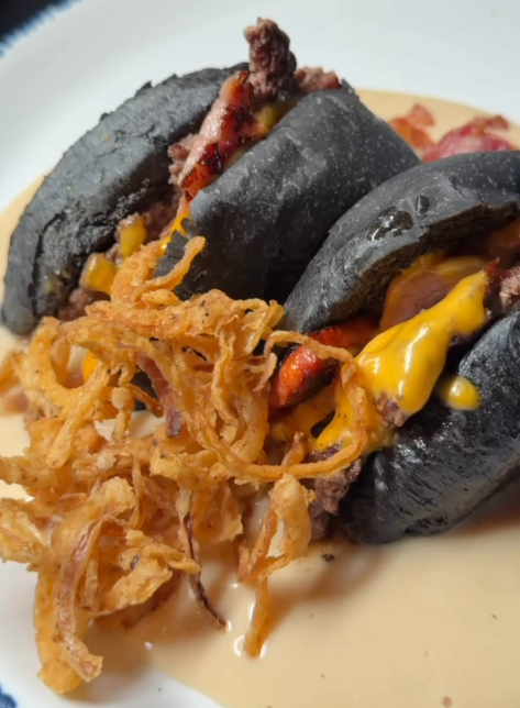 Black bun handheld with crispy onions